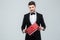 Confident attracive man in tuxedo standing and holding gift box