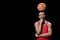 Confident basketball player posing with ball on head on black