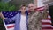Confident beautiful military woman in uniform and handsome teenage boy posing with American flag in slow motion standing