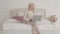 Confident blond Caucasian businesswoman typing on the laptop sitting on the bed at home. Young beautiful lady in