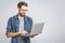 Confident business expert. Confident young handsome man in shirt holding laptop and smiling while standing against grey background