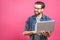 Confident business expert. Confident young handsome man in shirt holding laptop and smiling while standing against pink background