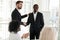 Confident businessman shaking hand of African American business partner