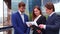 Confident businesspersons talking in front of modern office building. Businessmen and businesswoman have business