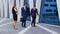 Confident businesspersons talking in front of modern office building. Businessmen and businesswoman have business