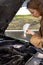 Confident caucasian woman driver checking oil level in car engine dipstick