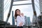 Confident and charming. Portrait of young Asian woman touching her chin with fingers at urban building background.