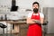 Confident chef. Restaurant or cafe cook. Mature male. Bearded man cook. Hipster in kitchen. Bearded man in red apron