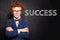 Confident child student with red curly hair with crossed arms against success inscription