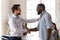 Confident company director shaking hands with happy african american employee.