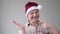 Confident content senior hispanic man in christmas hat pointing with forefinger aside