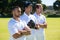 Confident cricket players standing at grassy field