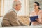 Confident dark-haired woman in clear glasses talking to old man