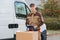 Confident Delivery Man With Parcels And Clipboard On Street