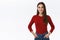 Confident, determined good-looking brunette girl in red sweater, holding hands in jeans pockets in self-assured pose