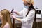 confident doctor dermatologist diagnoses the structure of hair of young woman using special tool