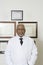 Confident Doctor With Framed Certificates Hanging On Wall