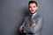 A confident elegant handsome young man standing in front of a grey background in a studio wearing a nice suit.