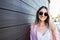 Confident and empowered young woman smiling and leaning on a wooden wall. Feminine determination