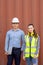 Confident engineers portrait in uniforms standing in front of the containers. Logistics and shipping. Professional occupation