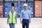 Confident engineers portrait in uniforms standing in front of the containers. Logistics and shipping. Professional occupation