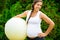Confident Expectant Female With Exercise Ball Standing In Park