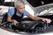 Confident Female auto mechanic examine car engine breakdown problem in auto service