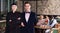 Confident female chef standing in restaurant hall with elegant waiter welcoming guests