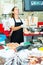 Confident female fishmonger working behind store counter, weighing fresh anchovies on scales