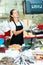 Confident female fishmonger working behind store counter, weighing fresh anchovies on scales