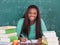 Confident female teacher writing in book at classroom desk