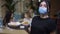 Confident female waiter in coronavirus face mask posing with seafood on tray and blurred clients sitting in restaurant