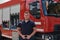 A confident firefighter strikes a pose in front of a modern firetruck, exuding pride, strength, and preparedness for