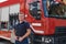 A confident firefighter strikes a pose in front of a modern firetruck, exuding pride, strength, and preparedness for