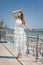A confident girl in a fantastic dress on a resort background. The charming girl in a white dress. Beauty and fashion concept.