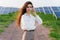 Confident girl stand and look into camera near solar panels row on the ground. Sustainability of planet. Green energy.