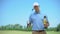 Confident golf player with gold cup and club smiling on camera, sport champion