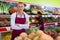 Confident greengrocery owner near shelves with fruits and vegetables