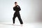 Confident guy in black kimono fighter posing in karate stance on studio background with copy space, mix fight concept