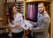 Confident handsome man with beard choosing a shirt in a suit shop.