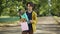 Confident handsome teenage boy standing in summer park with gift bag and bouquet of flowers. Portrait of adolescent