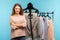 Confident happy woman, professional expert fashion stylist standing near clothes hang on shelf in designer store