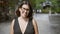 Confident hispanic woman, beautiful and joyful, cheerfully posing with glasses on, standing and smiling on kyoto\\\'s traditional