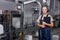 Confident industrial woman engineer in spectacles standing in factory at work place