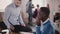 Confident male executive is helping his African American young colleague in modern light coworking, slow motion close-up