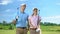Confident male and female golf players with clubs looking at course, sport game