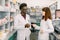 Confident Male And Female Pharmacists In Pharmacy. African man and Caucasian woman holding blister of pills while