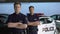 Confident male officers standing with hands crossed against police car, academy