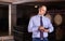 Confident male winemaker degusting red wine in wine cellar near bottles racks