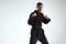 Confident man in black kimono fighter posing in karate stance on white studio background with copy space